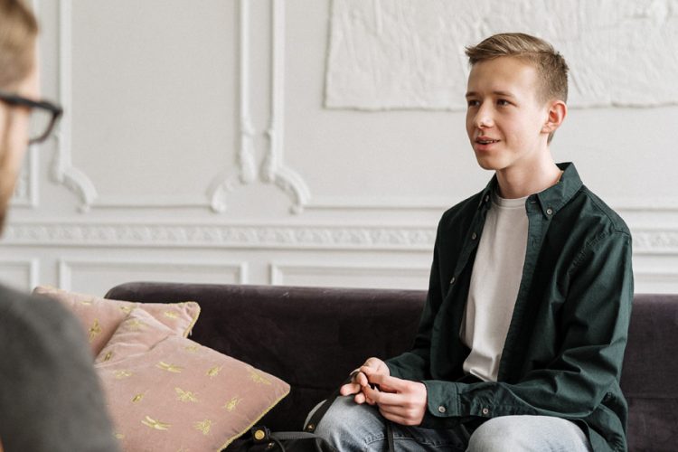 Young Person Sitting on a Couch Facing a Therapist
