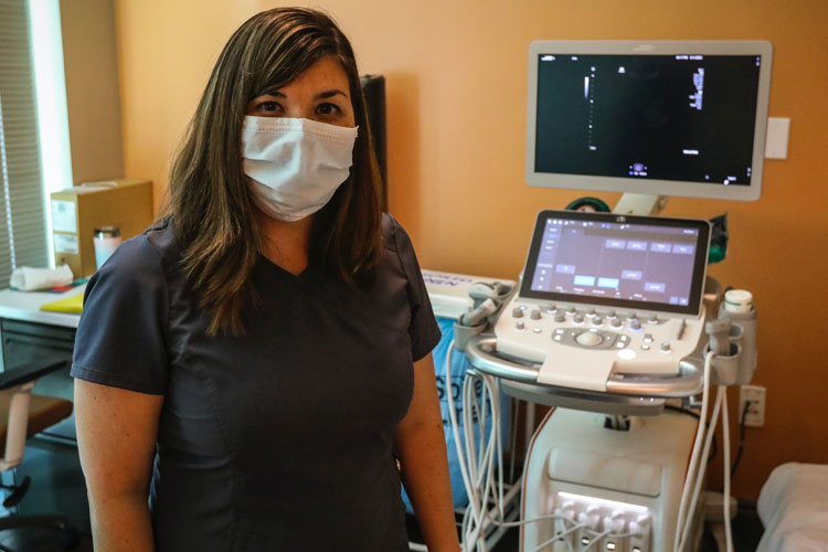 Person in mask standing in front of an ultrasound machine