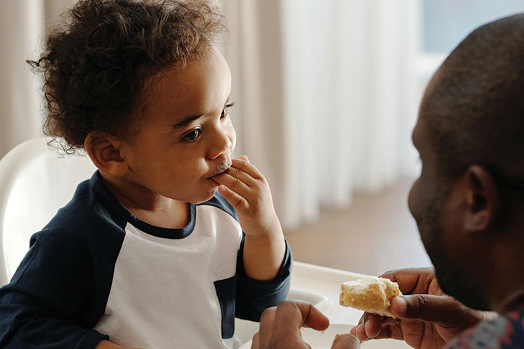 Paren feeding a child in a highchair