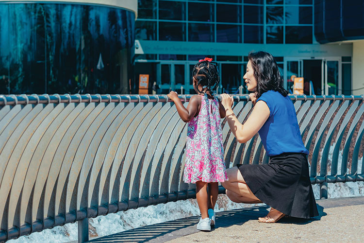 Adult and child looking over a walkway railing at buildings
