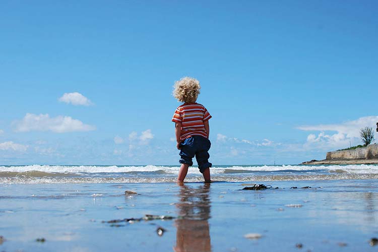 Child with curly hair in the surf
