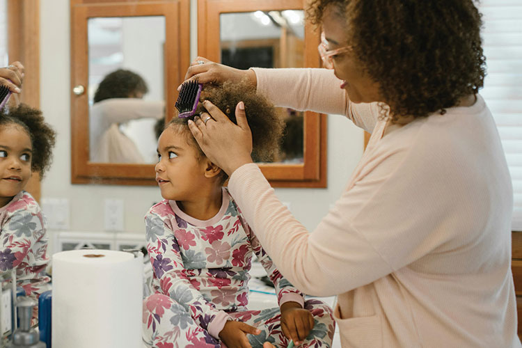 Parent combing the hair of a child in the bathroom