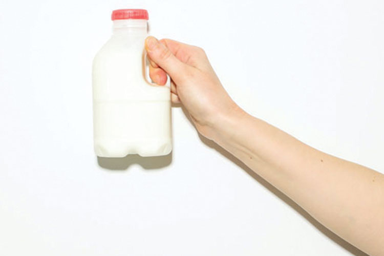 Outreached arm holding a small container of milk